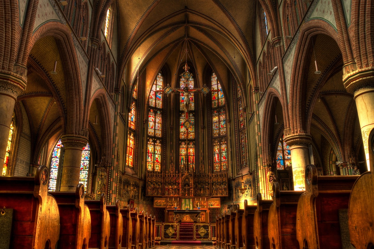 Gothic church nave with stained glass windows and the altar in warm light
