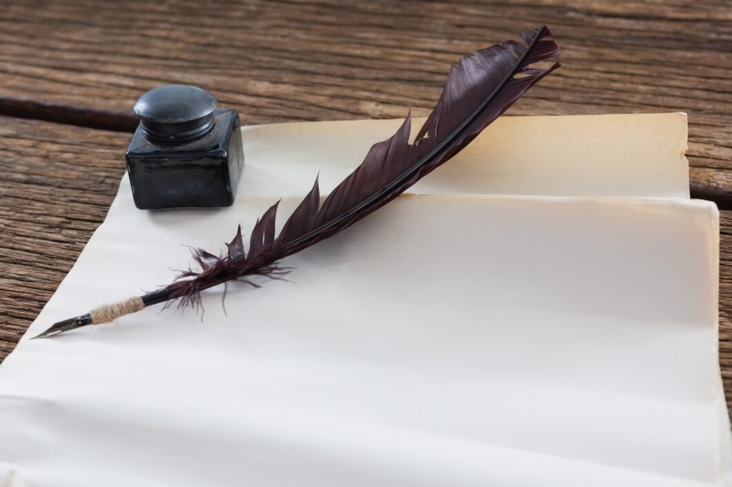 Quill pen and ink bottle beside blank parchment