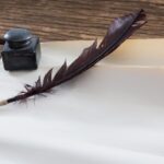 Quill pen and ink bottle beside blank parchment