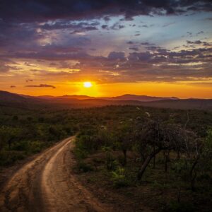 Dirt road toward mountains at sunset