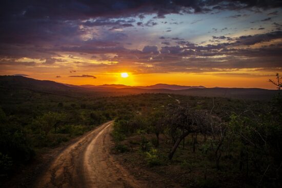Dirt road toward mountains at sunset