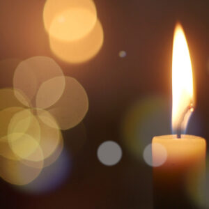 Single candle flame glowing in deep darkness
